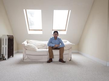 Photo of Jesus Martinez seated on a white couch in a room with skylights behind him