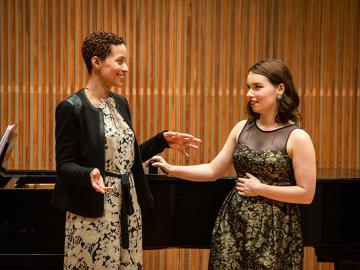 Jolly teaching student standing in front of piano