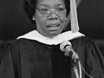 Maya Angelou at the podium in academic regalia. Black and white photo.