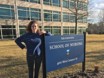 Maya Zeemont leans against the Yale School of Nursing sign