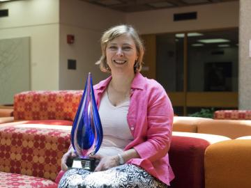 Megan Mitchell sits in the library holding her award