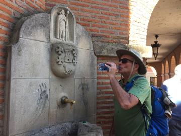 Michael Reynolds drinking water from a bottle in front of a water fountain