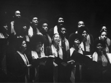 black and white image of choir members singing together.