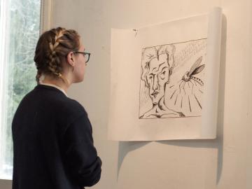 A student examines a print tacked to the wall.