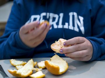 Close-up of a person peeling an orange.