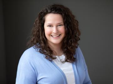 woman in light blue sweater and while top seated for photo.