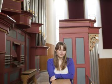 Katelyn Emerson ’15 posing next to an organ loft