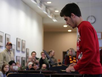 A student in a winter holiday sweater plays the marimba