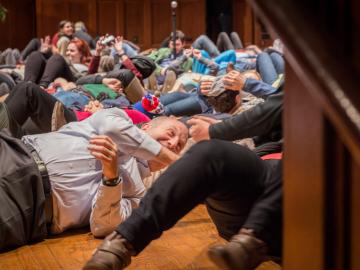 Students and President Krislov lie on the stage floor