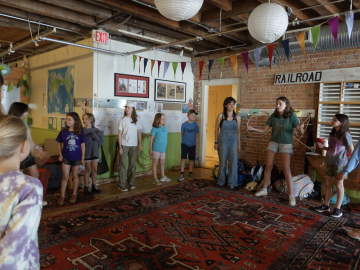 College interns and younger children stand in a circle