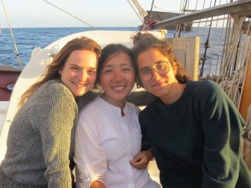 Three people leaning against each other, smiling on a boat. Photo.