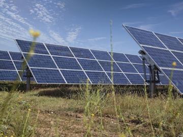 Three solar array panels unclose in grass field.