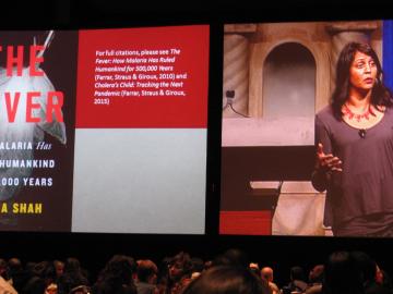 Sonia Shah with a screen showing the cover of her book, The Fever: How Malaria Has Ruled Humankind for 500,000 Years