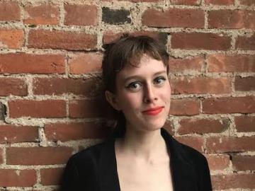 Sophie Kemp standing against a brick wall.