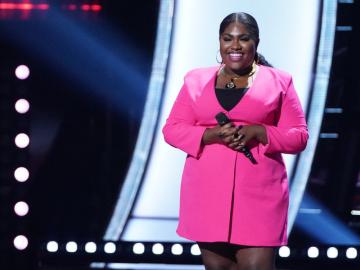 Black woman singer on stage dressed in pink outfit.