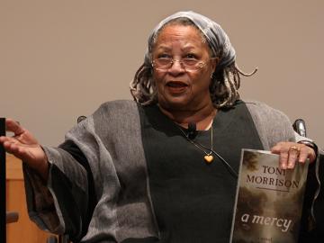 Toni Morrison wearing glasses and holding a book.