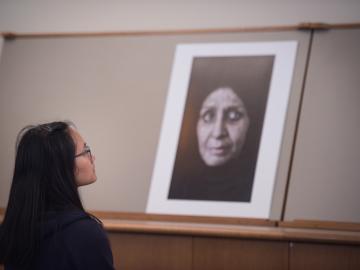 A student studies a large photo of the face of an older woman