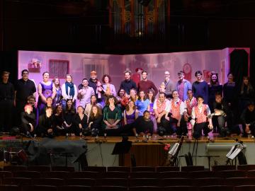 participants in an opera production gather together on stage