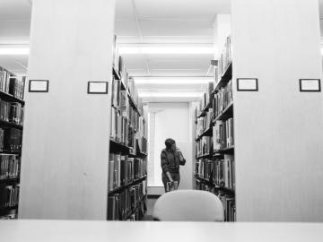 Student looking at books in the library 