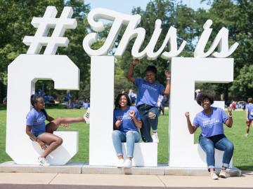 Students in matching Connect Cleveland t-shirts  sit on an outdoor sculpture representing the hashtag #ThisIsCLE