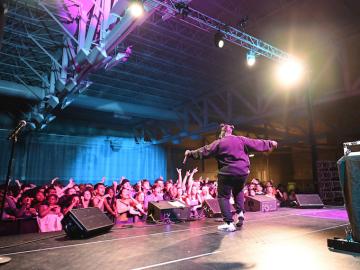 A rapper performs in front of a large crowd of excited students.