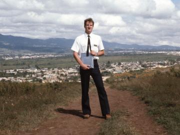 Man standing in front of landscape with mountains.