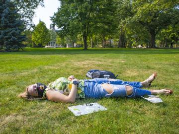 A girl laying in the grass in the park.
