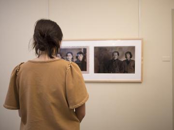 A student looks closely at a photo on a wall in a art museum classroom.