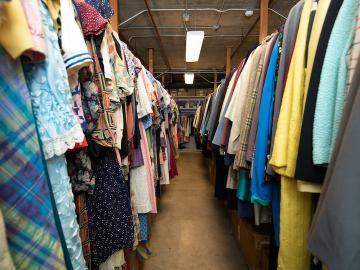 Two long rows of clothing hanging up on long pipes.