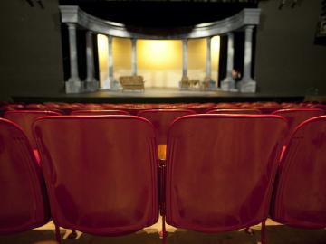 An empty auditorium facing a stage with columns on it.