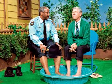 Two men sit with their feet in a child's pool.