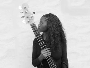 A girl holds a bass guitar in a portrait.