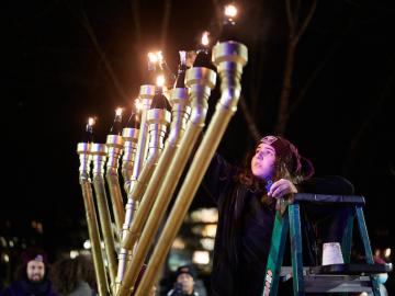 A girl lights a large menorah.