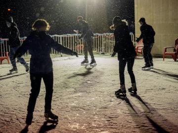 A group of people skate on an ice rink.