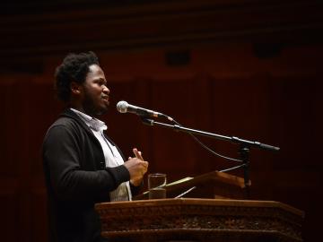 A man speaks into a microphone at a podium.
