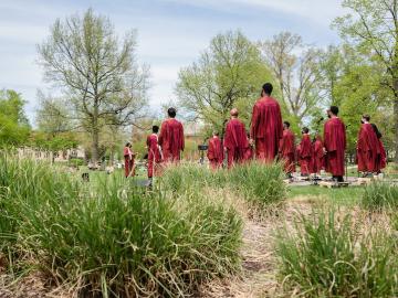 A group of people wearing choir robes stand in a field.