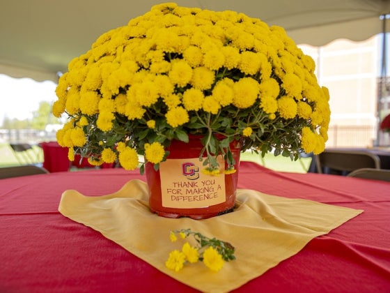 Yellow chrysanthemum centerpiece on a red tablecloth.