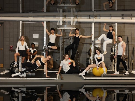 Students rehearsing a musical number on stage in a theater.