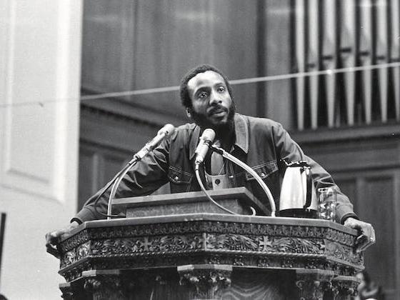Dick Gregory giving a speech at a podium.