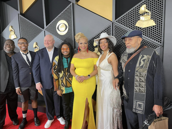 six people standing in front of Grammy Awards backdrop