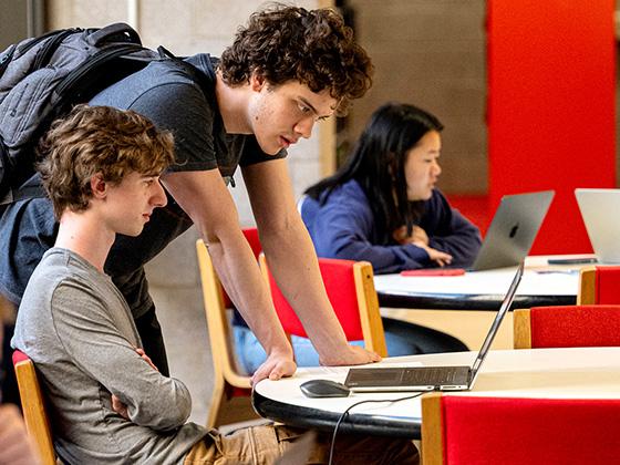 Two male students work together at a computer.