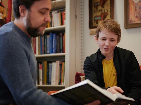 Mark discusses a book with a professor.