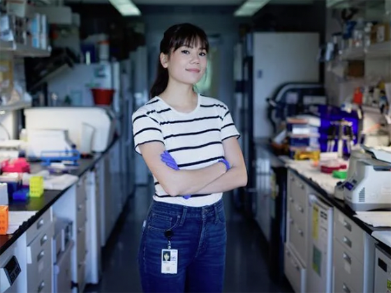 Gabby Walsh stands with arms folded in a research lab