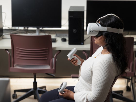 A person wearing goggles holds two joy sticks.