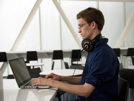 A student in a navy button-down shirt working on their laptop.