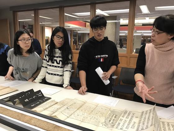 Three students and a librarian in the special collections room.
