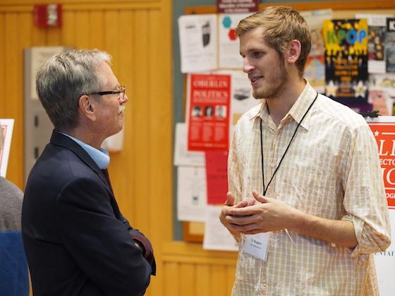A student talking to an older man in a suit.