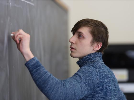 A student writes on a chalkboard.