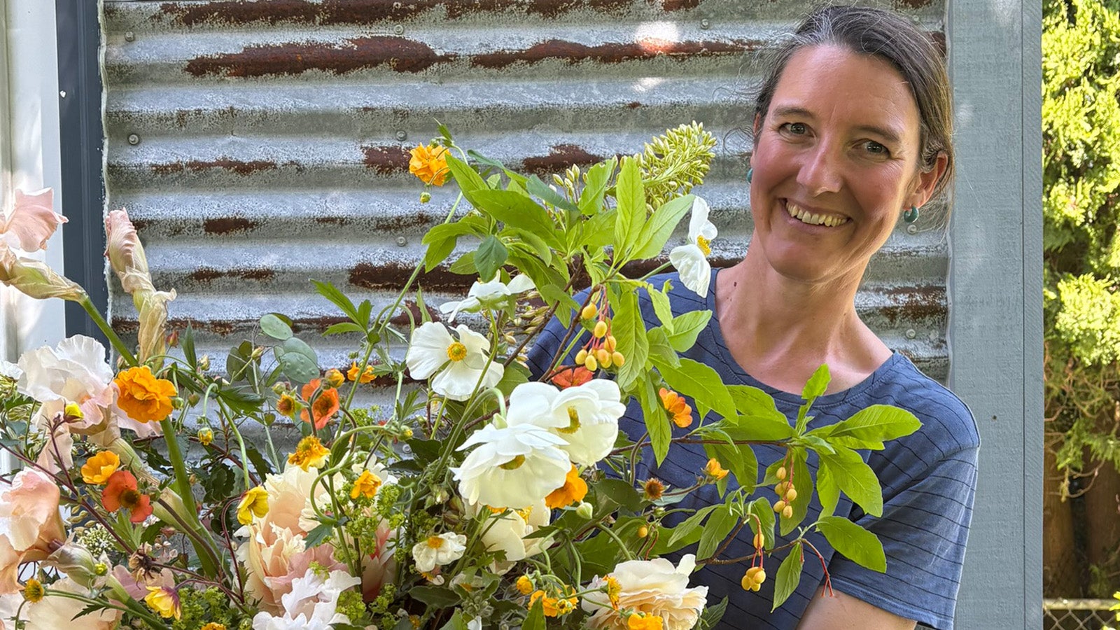 a person smiles behind a bouquet of flowers