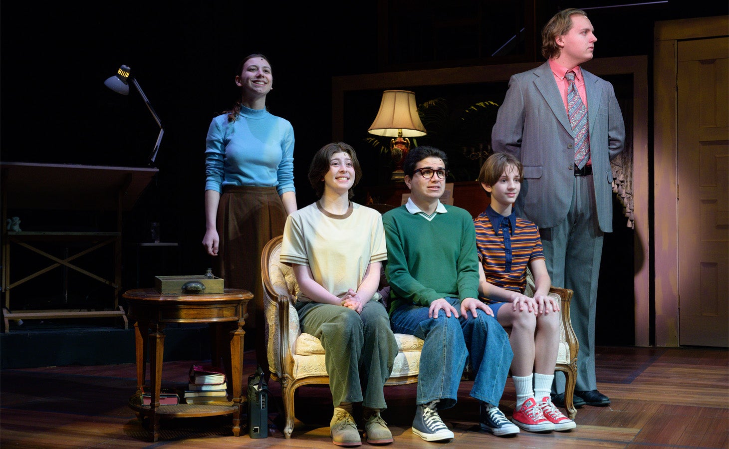the cast of fun home sitting on a couch onstage